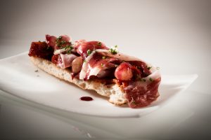 DRY-CURED ACORN-FED 100% IBÉRICO PORK HAM WITH ROASTED PEPPERS AND PICKLED ONIONS ON COCA BREAD